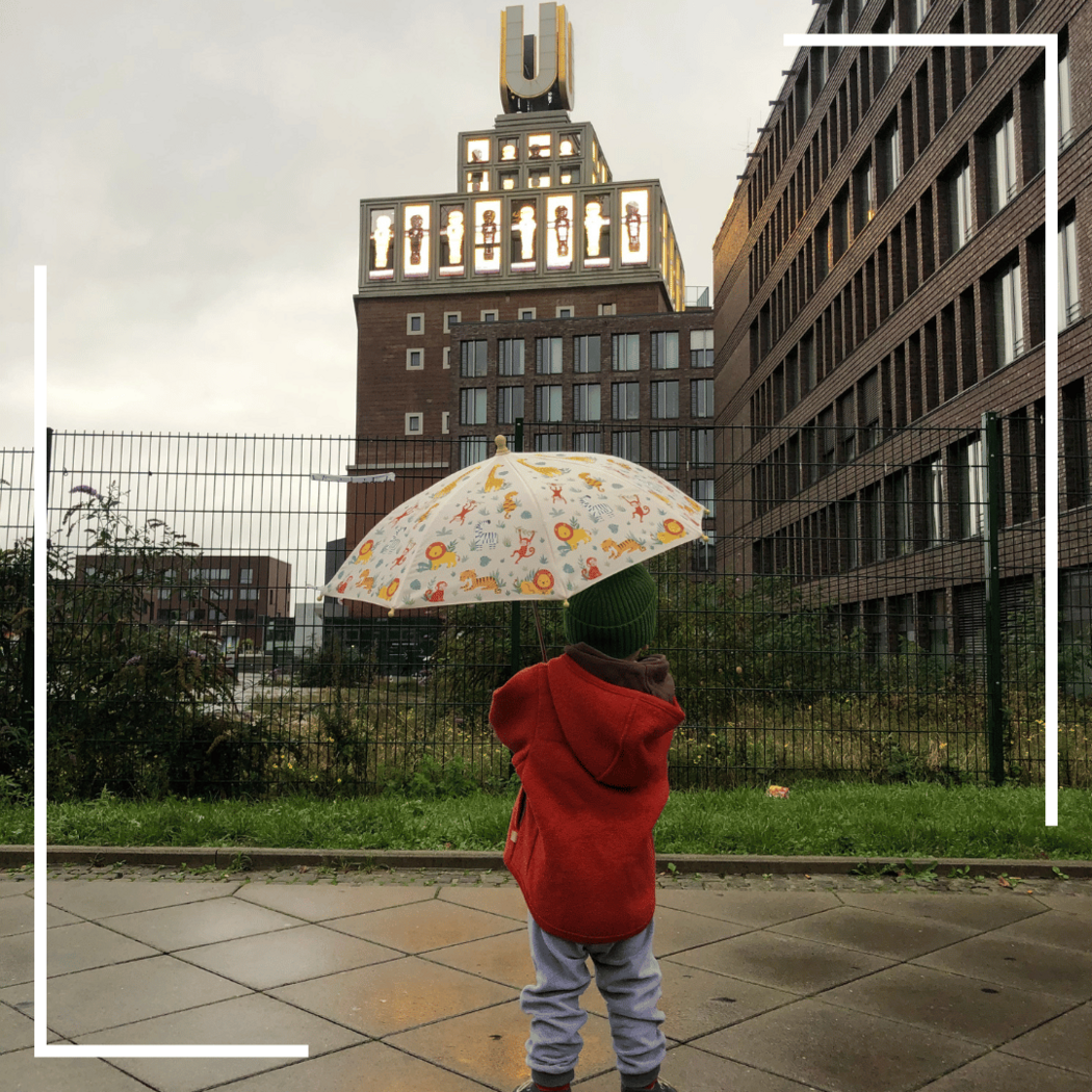 Kind mit Regenschirm schaut sich den U-Turm an