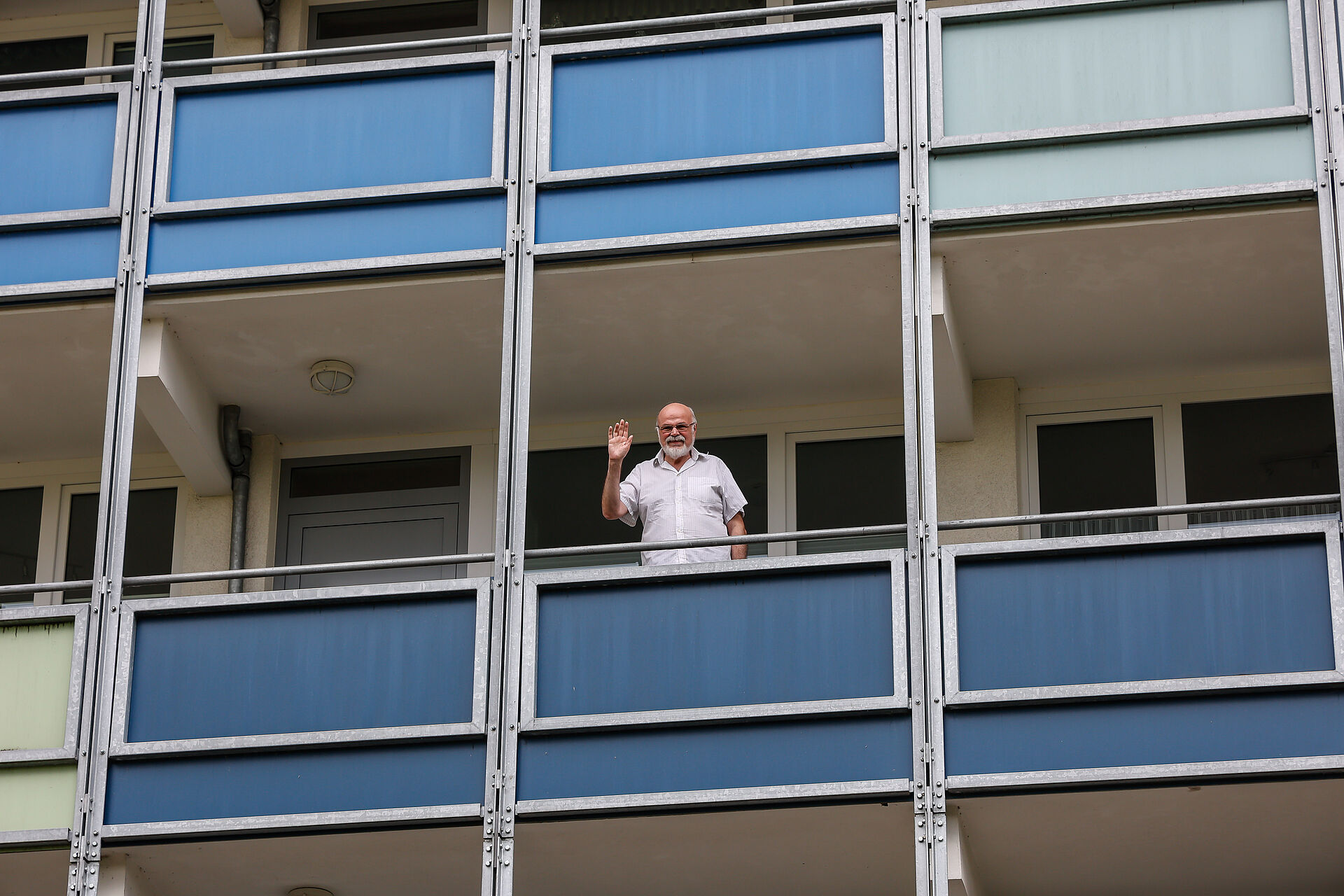 Älterer Herr winkt vom Balkon seiner Wohnung am Burgring in Dortmund