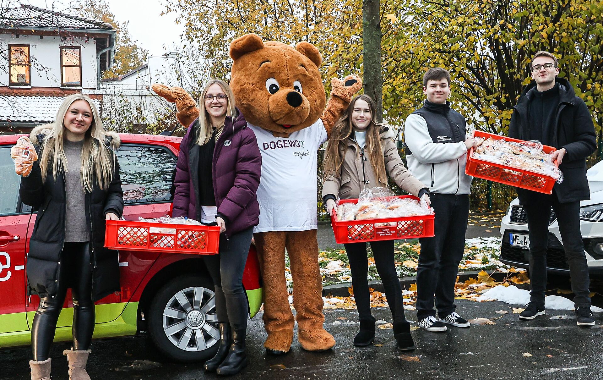 Fünf junge Menschen und das Maskottchen Dogibär posieren mit vielen Stutenkerlen vor der Kamera