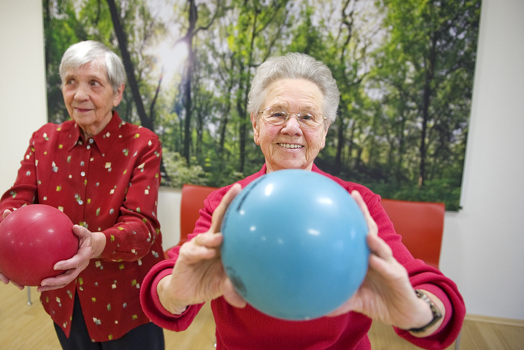 Zwei ältere Damen spielen lachend mit einem Ball