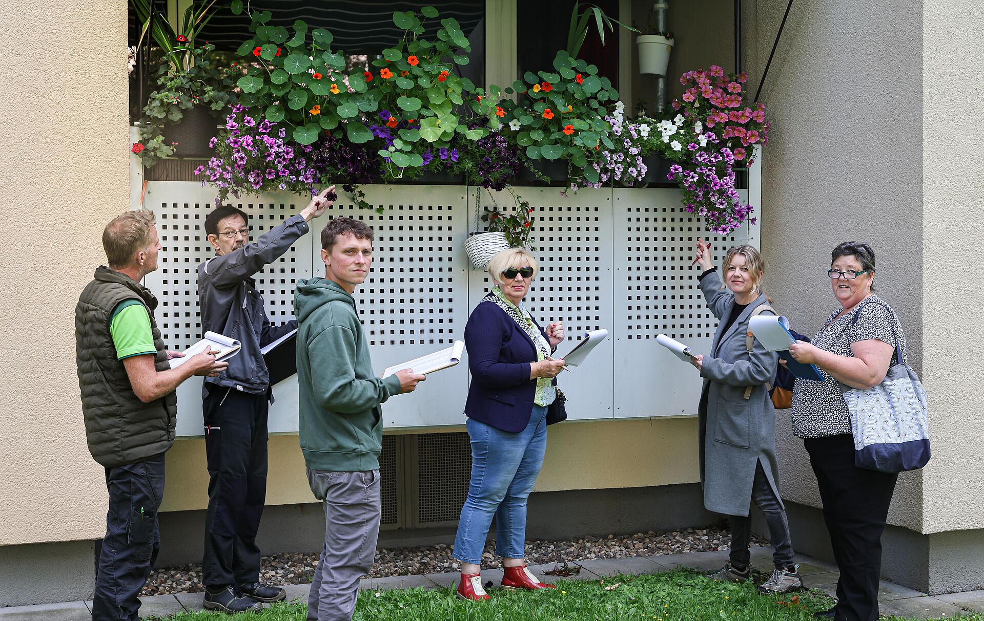 Mehrere Menschen stehen vor einem Balkon und betrachten die üppige Blütenpracht