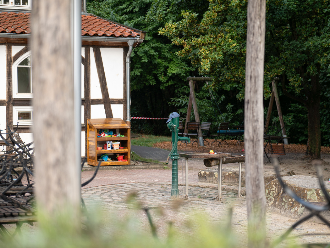 Blick auf einen Pumpbrunnen auf einem Wasserspielplatz im Grünen.