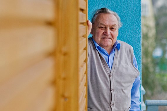 Älterer Herr grinst freundliche Hinter einer Hauswand hervor