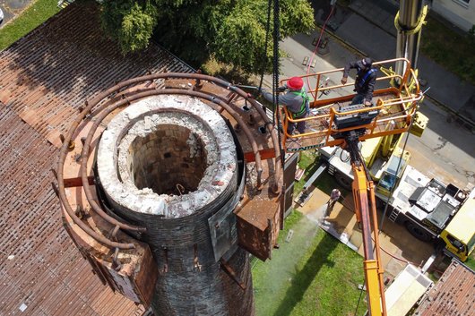 Zwei Männer arbeiten von einer Hebebühne aus an einem Schornstein in 30 Metern Höhe