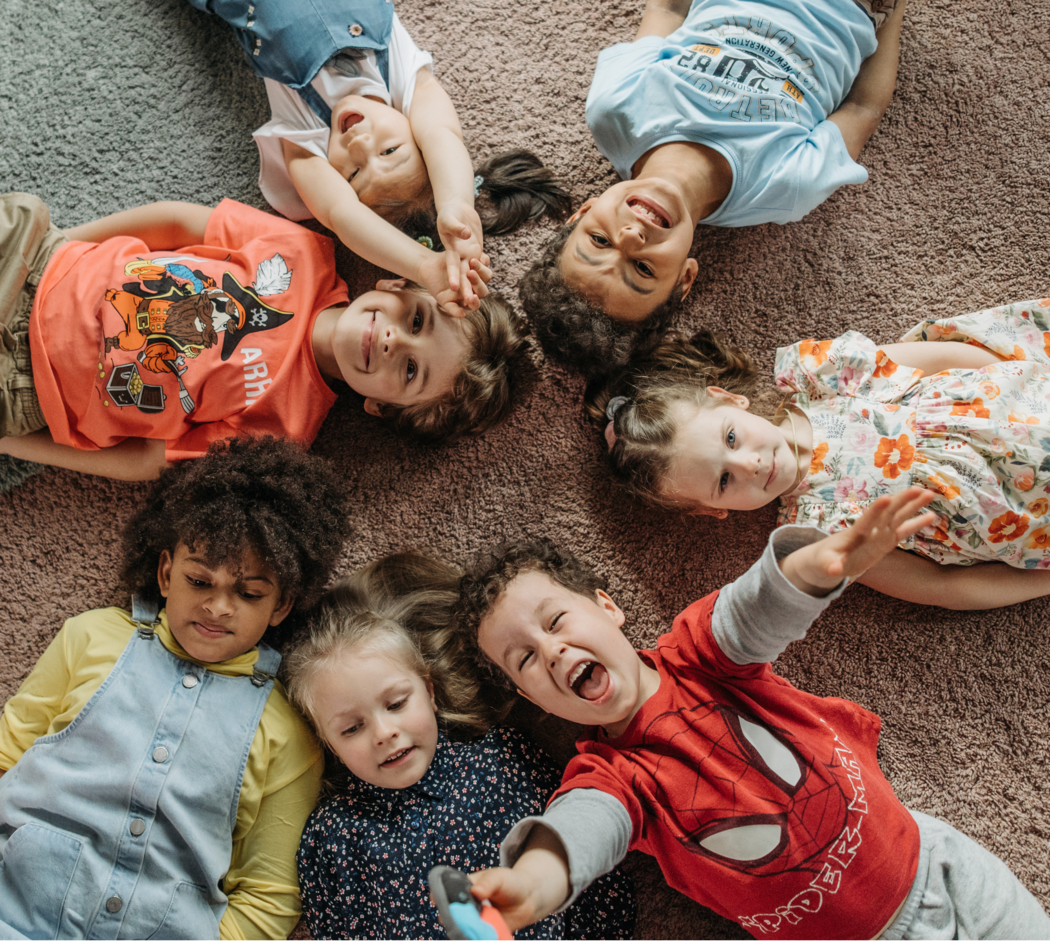 Kinder liegen im Kreis auf dem Boden