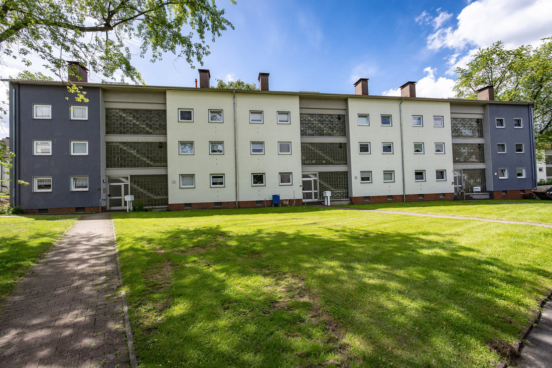 Drei Mehrparteienhäuser mit großflächigen Glasbausteinen mit großen Rasenflächen vor dem Haus.