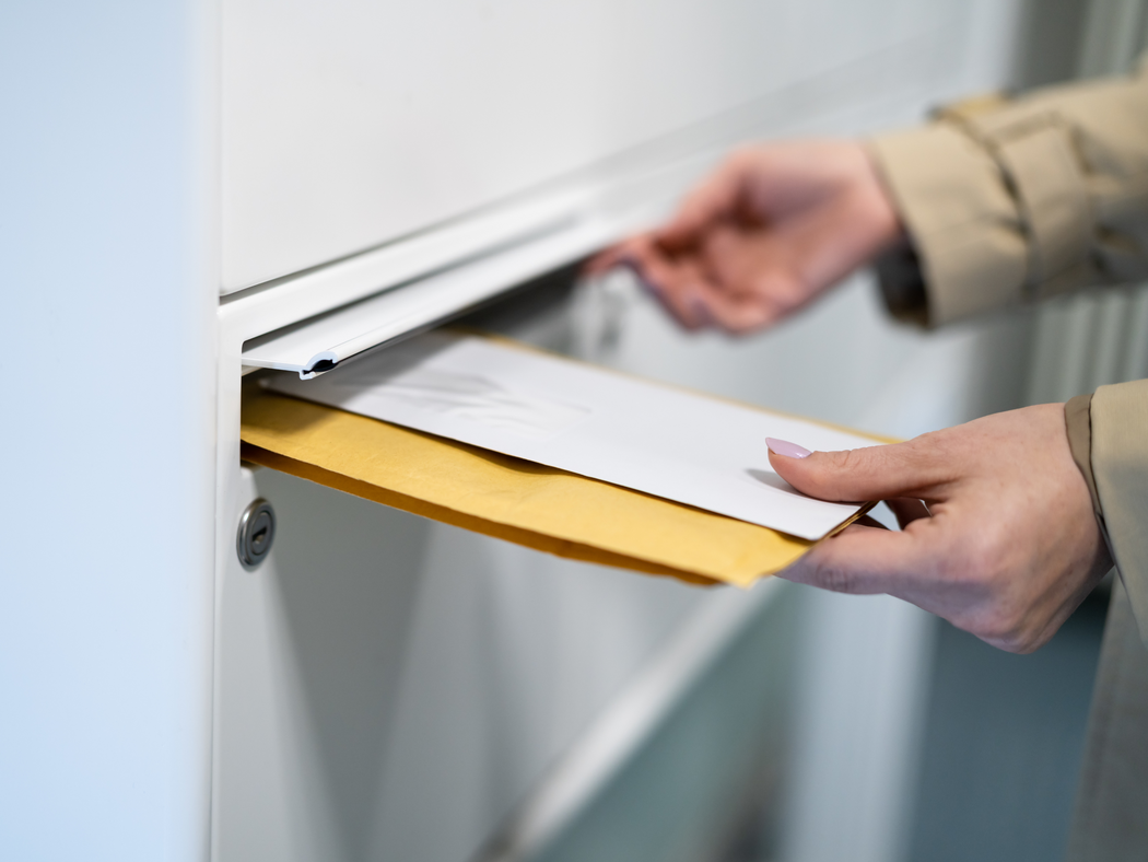 Eine Person, die Briefe in einen Briefkasten wirft.
