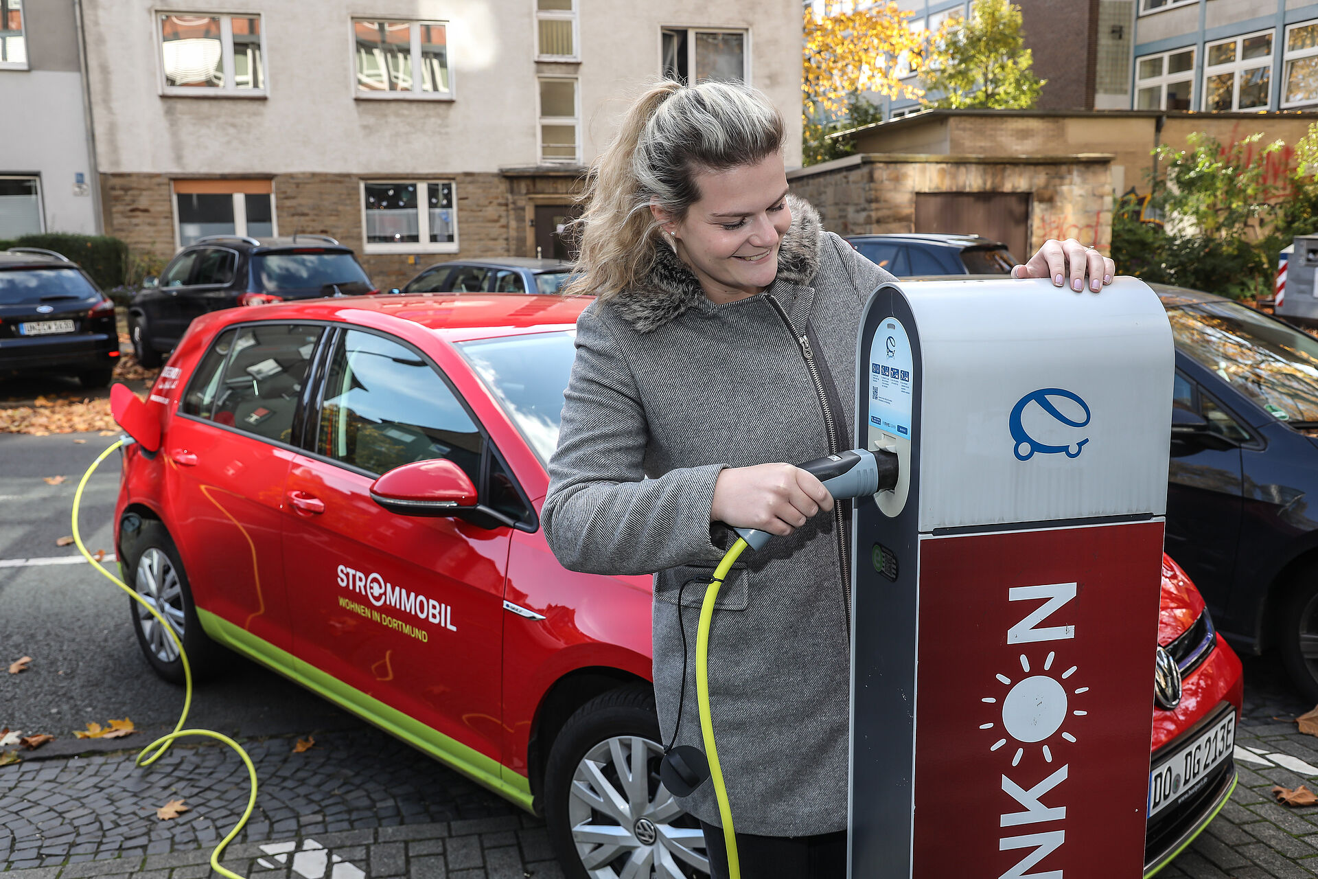 Mitarbeiterin von DOGEWO21 tankt ein E-Auto an einer Ladesäule