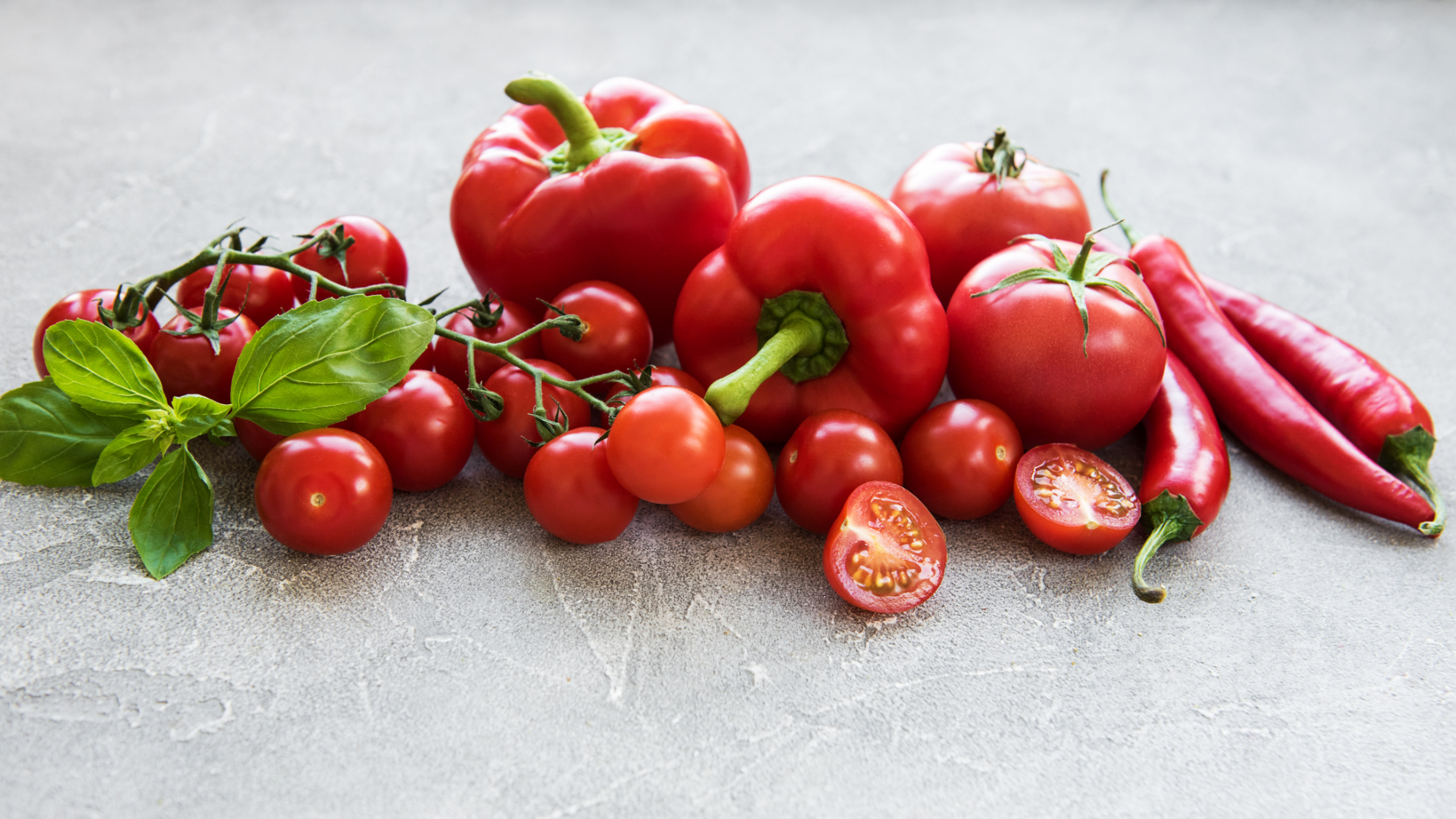 Rote Paprika, Kirschtomaten und Chili liegen auf einer Arbeitsplatte