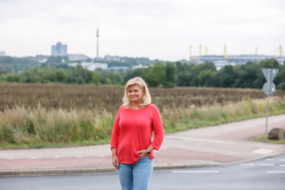 Mitarbeiterin von DOGEWO21 steht auf einer Straße vor einem Feld